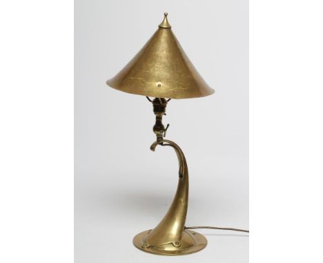 AN ARTS AND CRAFTS STYLE BRASS TABLE LAMP, early 20th century, the hammered conical shade with pointed finial on C scroll sup