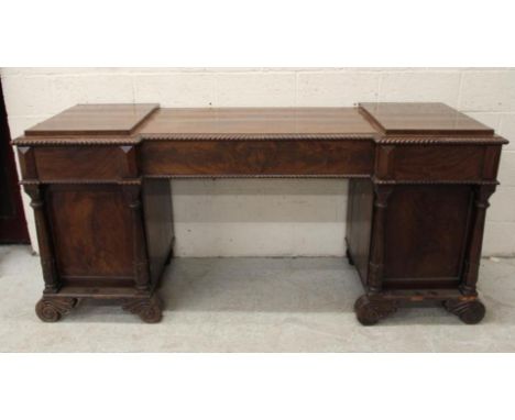 A REGENCY MAHOGANY PEDESTAL SIDEBOARD, of inverted breakfront form with stepped gadroon edged top, central long frieze drawer