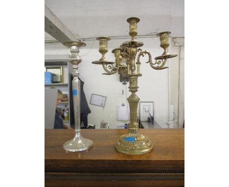 An ornate brass three-branch candelabra and a silver plated candlestick 