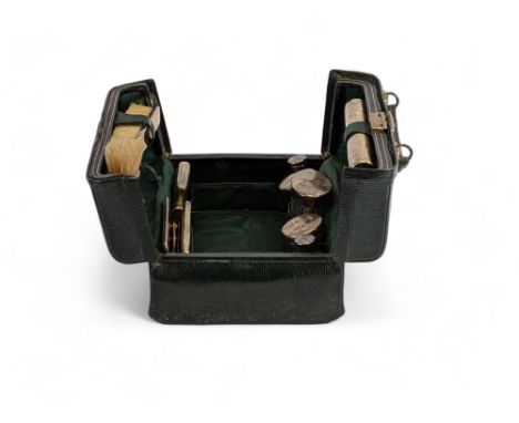 An early 20th century gentlemen's green leather travelling vanity case, with a canvas outer case, containing silver items hal
