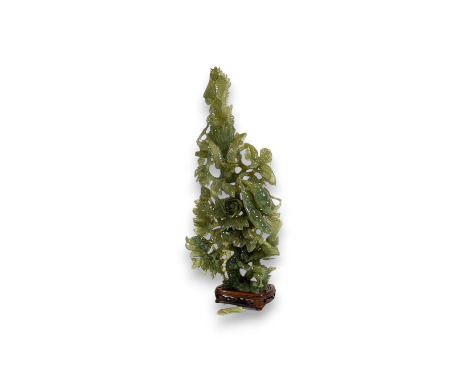 A Chinese faux jade sculpture, 20th century, in the form of a leafy, flowering stem, a dragon beneath, various birds perched 