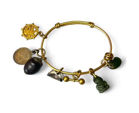 A charm bracelet, in precious yellow metal, featuring a nephrite jade kidney bean charm, a nephrite Maori deity, a yellow met
