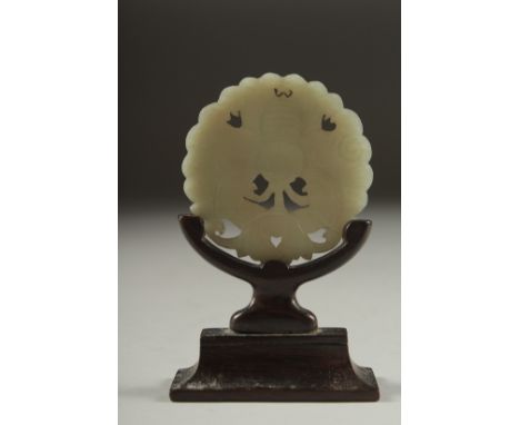 A CHINESE CARVED AND PIERCED JADE MOTH AMULET, on a fitted wooden stand, 6cm diameter.