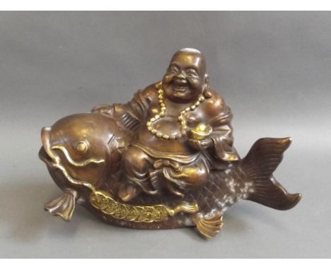A Chinese bronze figure of Buddha riding a carp with gilt highlights, 10½" long 