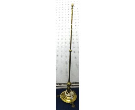 An old brass rising standard lamp for electric fitting on paw feet.