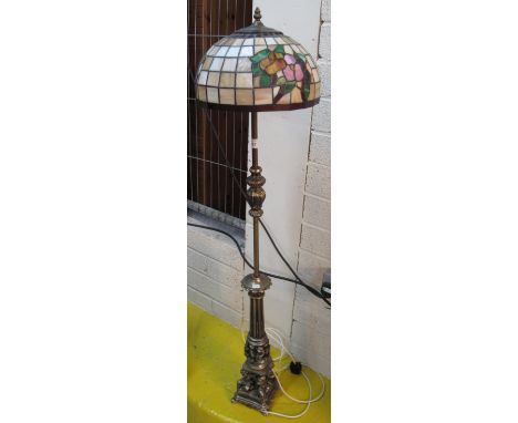 Modern brass standard lamp with relief cherub figures and a Tiffany style glass shade.