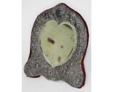 A late Victorian/Edwardian silver framed mirror, the heart shaped bevelled mirror within an embossed and pierced silver borde