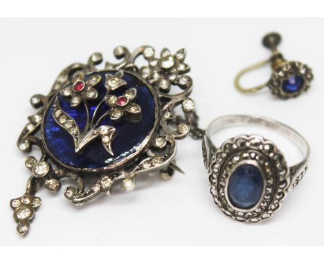 A white metal and enamel pendant brooch set with paste, length 42mm, together with a blue paste and marcasite ring, size M, a