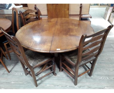 A reproduction oak extending pedestal dining table with single leaf and four ladder back and rush seated chairs, table dimens