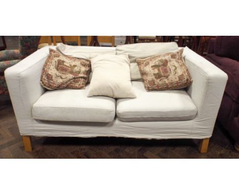 A cream 2 seater modern sofa with scatter cushions