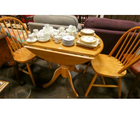 A modern light wood kitchen drop leaf table and a pair of matching hoop back stick chairs 