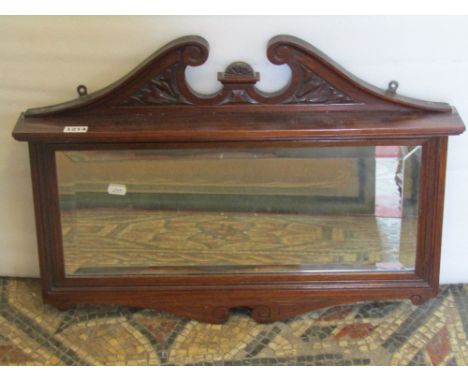 A small Edwardian wall mirror of rectangular form with bevelled edge plate within a moulded frame with raised architectural b