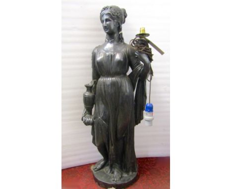 A large floorstanding plaster lamp in the form of a classical maiden holding a water jug/urn, with all over ebonised painted 