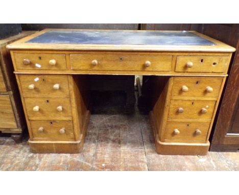 A small late 19th century oak pedestal desk of nine drawers with inset leather top, 122cm wide