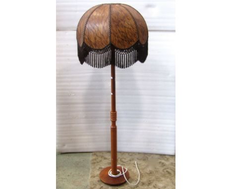 A mid 20th century teak standard lamp, with partially ring turned column and disc shade platform base beneath a woven domed p