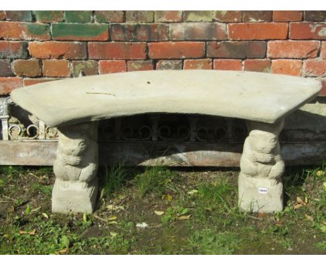 A contemporary cast composition stone garden bench, the curved slab seat raised on a pair of novelty column supports in the f