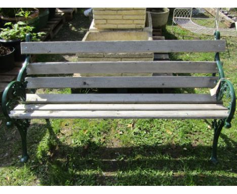 A Victorian style three seat garden bench with timber lathes raised on a pair of decorative green painted cast aluminium end 