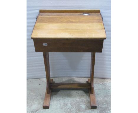 A vintage oak framed child's school desk with hinged slope, pen channel and inkwell