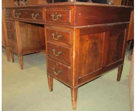 An Edwardian walnut kneehole twin pedestal writing desk with inset leather panelled top over an arrangement of nine frieze dr