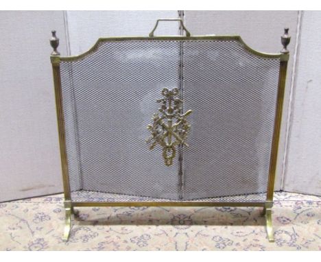 An Edwardian style firescreen with reeded brass frame and cast brass central motif, 67cm wide