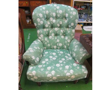 A button upholstered chair in green and white floral fabric