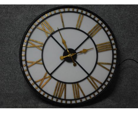A light up glass fronted shop display clock with gilded roman numerals and movable hands. 80x80cm 