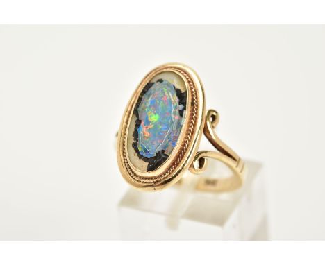 A YELLOW METAL RING, of oval design, set with a broken opal triplet, within a collet mount and rope twist surround, scroll de