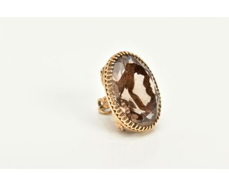 A 9CT GOLD SMOKEY QUARTZ FOB, of oval design with a claw set oval cut smokey quartz, embossed scroll detailed handle and jump