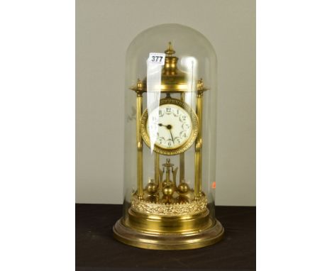 AN EARLY 20TH CENTURY GERMAN BRASS ANNIVERSARY CLOCK, the domed canopy on six columns, the enamel dial with Arabic numerals a