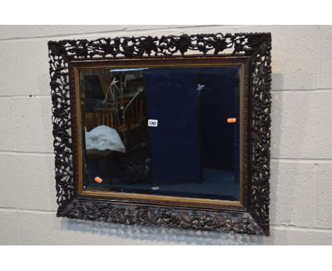 A LATE 19TH CENTURY OAK FRAMED BEVELLED EDGE WALL MIRROR, the frame with depicting carved fruiting vine, grapes and a small w