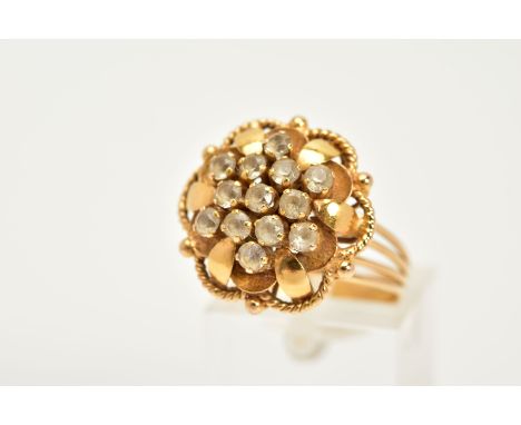 A YELLOW METAL CLUSTER RING, in the form of an openwork flower, set with circular cut colourless stones, assess as synthetic 