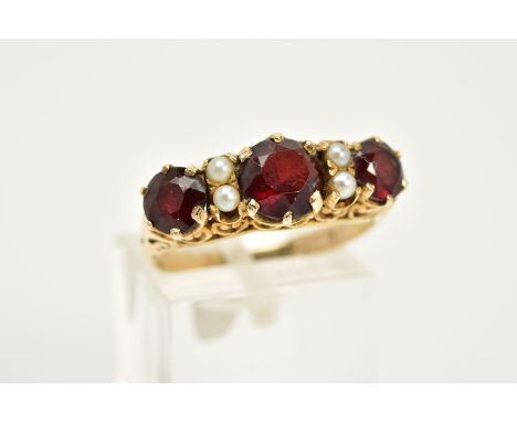 A 9CT GOLD GARNET AND PEARL RING, designed with three circular cut garnets interspaced with seed pearl detailing , within an 