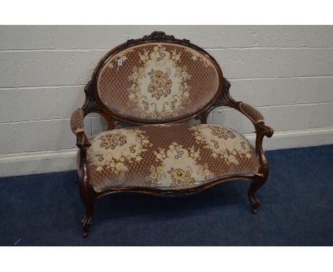 A VICTORIAN WALNUT TWO SEATER SOFA, with foliate decoration, oval back to swept open and scrolled armrests on cabriole front 