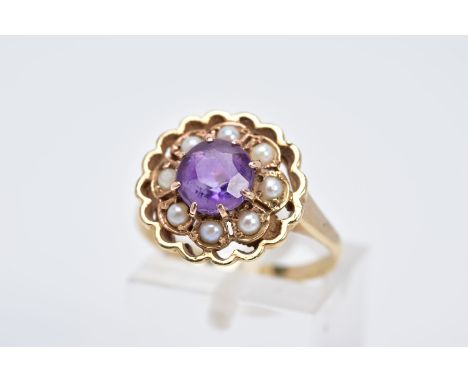 A YELLOW METAL AMETHYST AND SEED PEARL CLUSTER RING, the openwork raised floral cluster, set with a central circular cut amet
