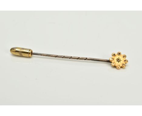 A YELLOW METAL DIAMOND SET STICK PIN, of a flower shape design, with a star set rose cut diamond, within a rope twist and bea