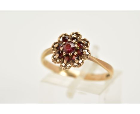 A 9CT GOLD GARNET CLUSTER RING, of an openwork floral design set with nine circular cut garnets, within an openwork rope twis