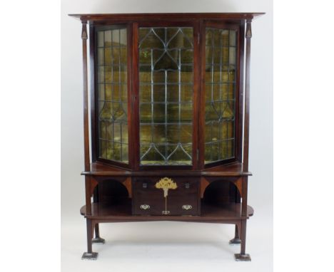 An Arts and Crafts mahogany display cabinet, circa 1910, the flat cornice above a ribbed glazed leaded light door with three 