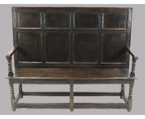 An oak panel back settle, 18th century and later, the indented panel back, incised with a simple arabesque design above a ben