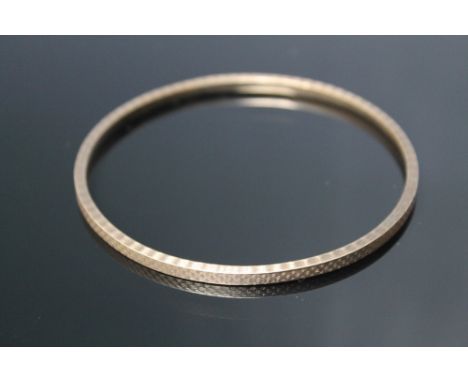 A HALLMARKED 9 CARAT GOLD BANGLE, having an engine turned design to both top and sides, approx weight 21.6 g, Dia. 8 cm 