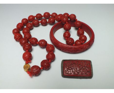 A COLLECTION OF CHINESE RED CINNABAR LACQUER JEWELLERY, consisting of a bangle, a carved bead necklace with yellow metal clas