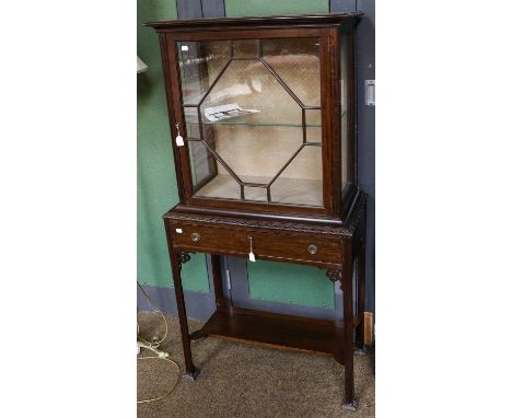 An Edwardian mahogany display cabinet on stand, with single drawer and raised on reeded square supports, heavily capped feet,