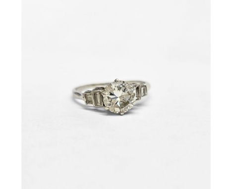 A platinum diamond solitaire ring, flanked by two baguettes to each shoulder, total weight 3.2g, size P. (Diamond 7.01mm diam