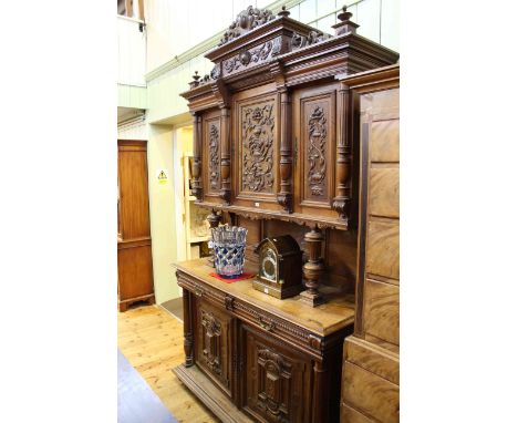 Late 19th Century Continental carved cabinet, the upper section having three carved panel doors, raised on turned pillars abo