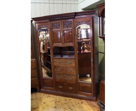 Late 19th Century/early 20th Century carved mahogany combination wardrobe having two carved panel doors above four drawers fl