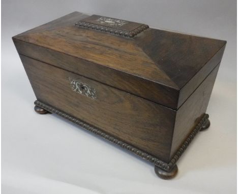 A 19th Century rosewood tea caddy of sarcophagus form, the top opening to reveal a bowl recess flanked by two canisters, rais