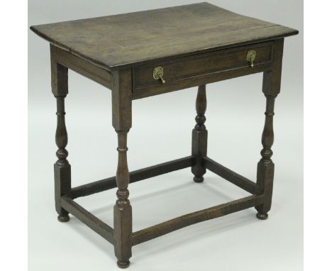 An oak side table in the early 18th Century manner, the plank top above a single frieze drawer with brass drop handles, raise