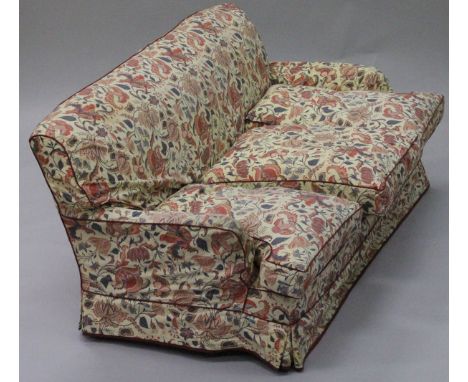 A 20th Century three seat sofa in the Howard manner, with cream ground foliate patterned loose covers, on turned front legs, 