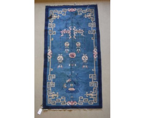 A Chinese rug, the central panel set with decorative lantern and floral design on a blue ground, within a Greek key style bor
