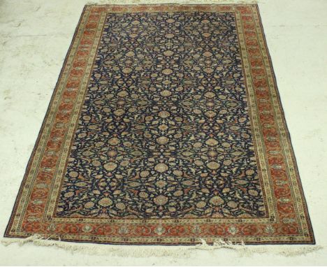 A Persian carpet, the central panel set with all over floral decoration on a blue ground, within a stepped pink, cream and gr