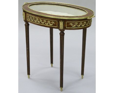 A 20th Century Louis XVI style mahogany bijouterie table of oval form, the glass based tray top with buttoned silk interior, 